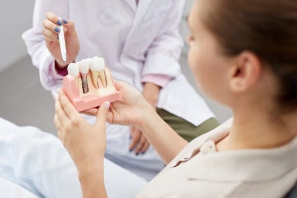 A woman holds a tooth model in her hand, demonstrating dental education or oral health awareness.