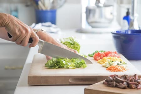 Close up of woman preparing a healthy meal and cutting lettuce