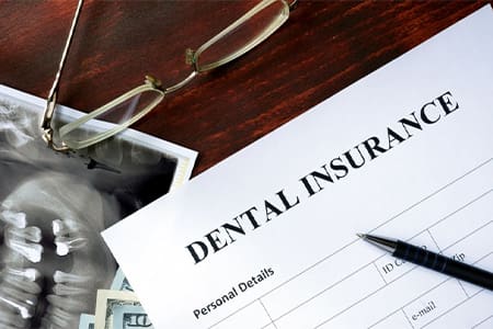 Paperwork titled dental insurance sitting on a wood desk