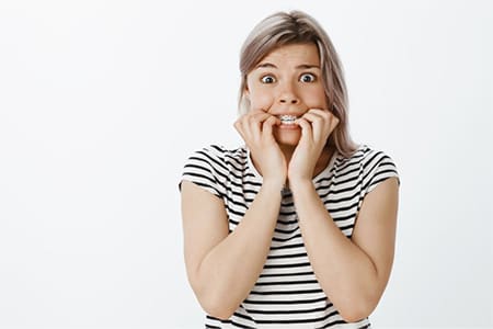 Woman biting her nails on white background