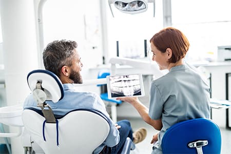 Smiling dental assistant and patient looking at X-ray