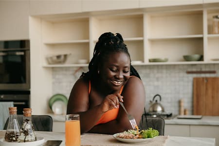 Woman smiling while eating lunch in kitchen