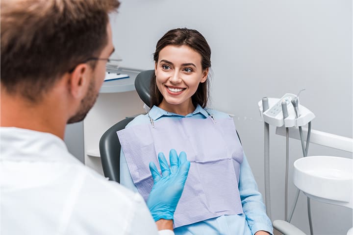 A young and smiling woman talking with her dentist