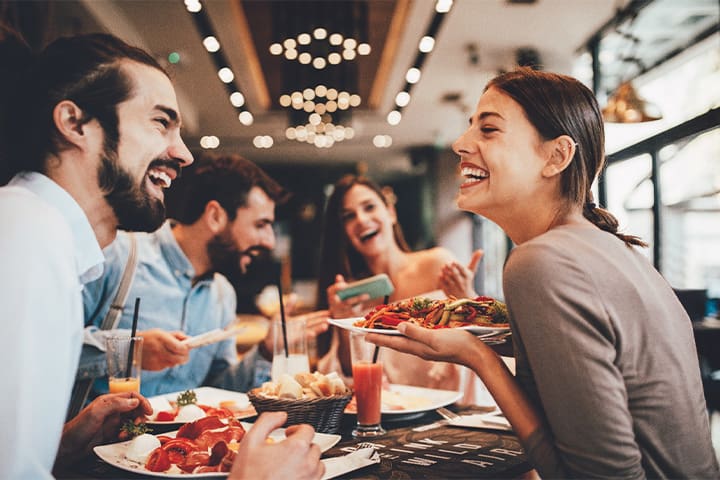Veneers patient in Weston smiling with friends at restaurant