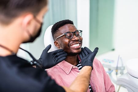 Dentist looking at patient's smile in treatment room.