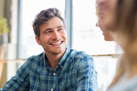 Man in blue shirt smiling at friend.
