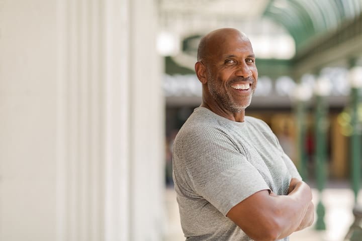 Man in gray shirt smiling outside.