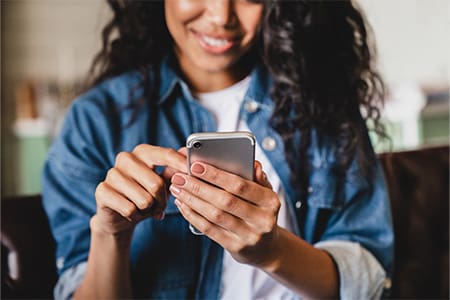 Smiling woman looking at phone at home.